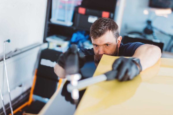 Car mechanic working to remove dent in workshop. Professional car detailing service